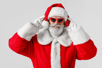 Cool Santa Claus listening to music on grey background
