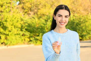 Young allergic woman with nasal drops outdoors