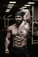 Fototapeta na wymiar angry strong caucasian man in bandana showing abdominal and oblique muscle in sport fitness gym