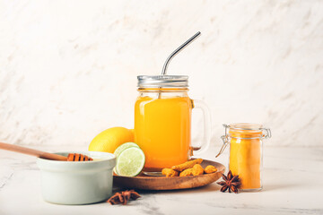 Mason jar of healthy turmeric drink on white table