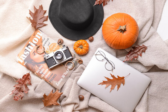 Autumn composition with stylish clothes, laptop, magazine and photo camera
