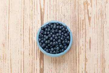 Organic blueberries in bowl on white wooden board background, top view. Healthy eating