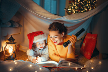 mother reading book to daughter near Christmas tree