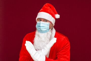 Closeup santa claus costume rejection crossing arms and palms doing negative sign,wears medical mask