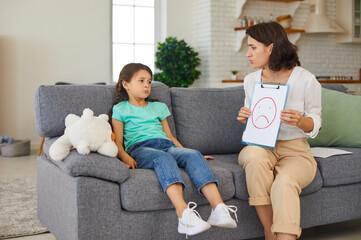 Child psychologist having therapy session with little girl discussing and portraying emotions