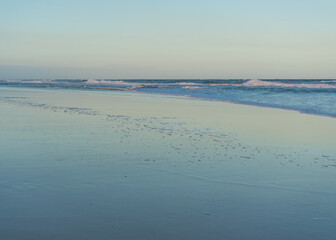 Low angle photo of bubbles and waves at the water's edge at sunset