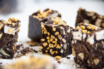 Close-up of chocolate chunks with puffed rice, nuts and marshmallows, on a light background with a blurred background