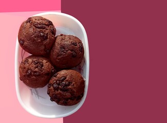 Chocolate chip sprinkled cup cakes in white paper on a plate. Top view. Selective focus. Colourful mauve pale pink background. food, snack for party, celebration purpose.