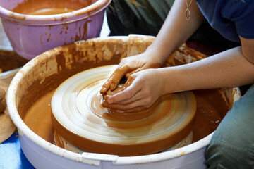Hands of a potter who makes a pot of clay on a potter's wheel
