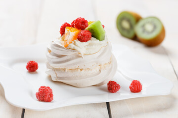 Pavlova sweet cream dessert with berries and fruits on white wooden background. Delicious food.