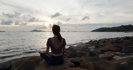 Woman do yoga and sit beside the sea