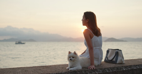 Naklejka na ściany i meble Woman enjoy sunset view with her dog