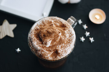 Cup of coffee with milk foam and cocoa with decorations on the background.