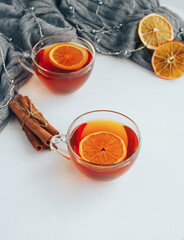 Hot spicy autumn tea with lemon and cinnamon on white table and gray cozy plaid - 392786882