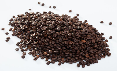 Pile of aromatic roasted coffee beans on white surface..