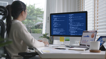 Back rear view of young asian woman, freelance data scientist work remotely at home coding...