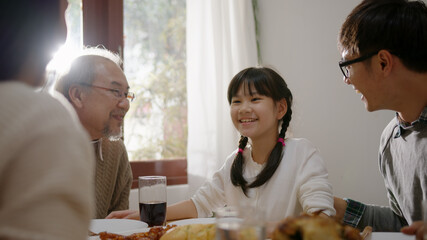Happy asian family enjoy breakfast together. Cheerful parents, grandfather and cute daughter enjoy breakfast together on dining table at home. wonderful moment family