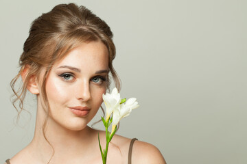 Natural beauty woman with freckles skin and ginger hair holding flower on white background