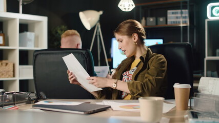 Successful woman discussing documents with attractive guy in stylish office.