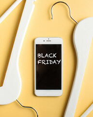  Black friday sales concept. Empty hangers and mobile phone