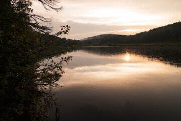 A beautiful view by the lake during sunset on a summer evening. Forest lake with mountains around