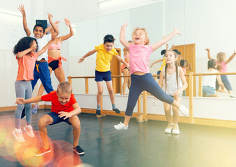 Happy kids of different nationalities and ages jumping during class in dance school