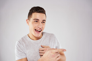 Man in a white t-shirt emotions gestures with hands close-up cropped view light background