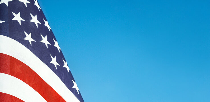 Closeup of an American flag waving in the wind against blue sky. Copy space. 