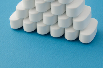 pharmacy theme many white pills tablets on blue surface with copy space