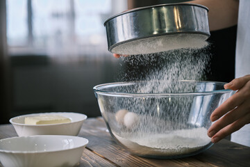 Female hands Sift flour in a glass bowl