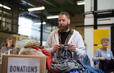 Volunteers sorting out donated clothes in community charity donation center.