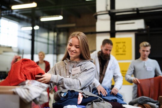 Volunteers Sorting Out Donated Clothes In Community Charity Donation Center.