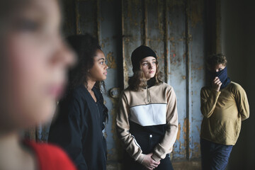 Group of teenagers gang standing indoors in abandoned building, bullying concept.
