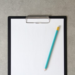 Template of white paper with simple pencil on light grey concrete background in a black tablet with a clip. Concept of new idea, business plan and strategy,  empty space for text