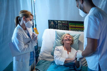 Doctors and recovered covid-19 patient in bed in hospital, coronavirus and recovery concept.