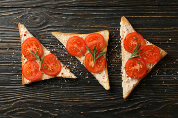 Concept of breakfast with toasts with tomato on wooden background