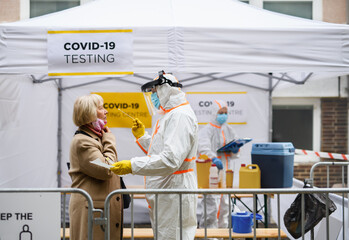 Senior woman in covid-19 testing center outdoors on street, coronavirus and swab taking concept.
