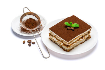 Traditional Italian Tiramisu square dessert portion on ceramic plate and strainer with cocoa powder isolated on white background with clipping path