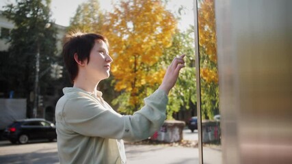 Woman using touch screen terminal in the street. Big navigation touch screen, touch screen outdoor on street.