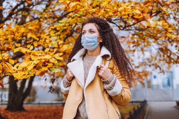 Beautiful afro haired woman wearing protective medical face mask stand on the street of city....