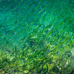 Abstract image of ripples in the pure water of translucent turquoise mountain lake in Marguzor, Tajikistan
