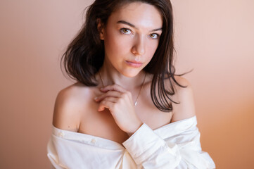 Beautiful young woman posing on beige wall background.