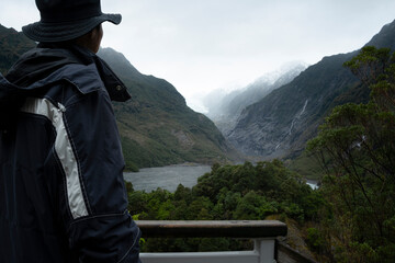 Tourist enjoying the view of Franz Josef Glacier at the viewing platform, South Island, New Zealand