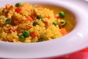 Plain vegetable rice and healthy green vegetables served in a white plate over red plaid background tablecloth.