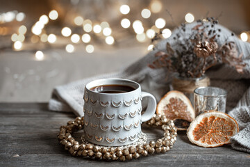 Cozy composition with a Christmas cup on a blurred background with lights.