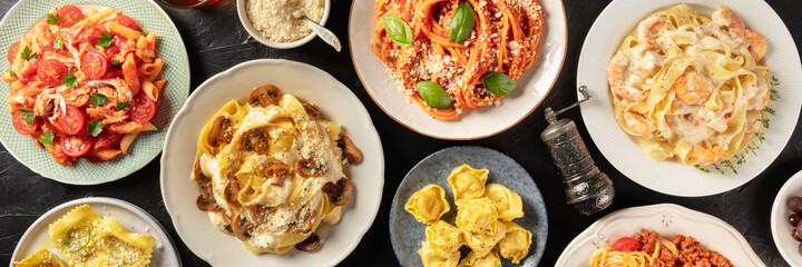 Pasta variety panorama. Chicken, mushroom, vegetable, seafood, and meat pastas. shot from the top in a flat lay on a black background, with grated Parmesan cheese