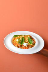 Italian pasta with cheese on hand over pastel colored background.