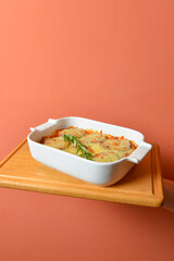 Italian casserole with cheese and vegetables on hand over pastel colored background. Delicious Italian cuisine concept.