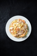 Italian pasta. Pappardelle with shrimps and creamy sauce, shot from above with thyme and a place for text, on a black background
