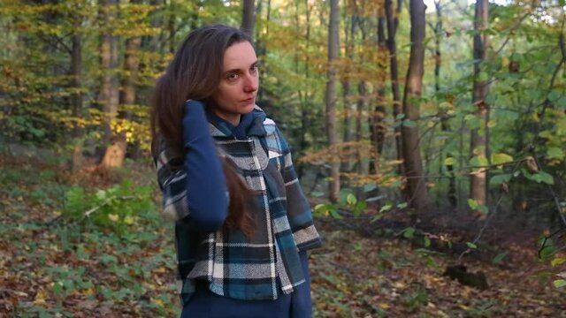 Young woman plays with hair on the background of autumn scenery